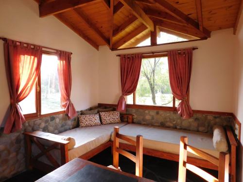 ein Sofa im Wohnzimmer mit Fenstern in der Unterkunft Cabañas Aldea de Montaña in Lago Puelo