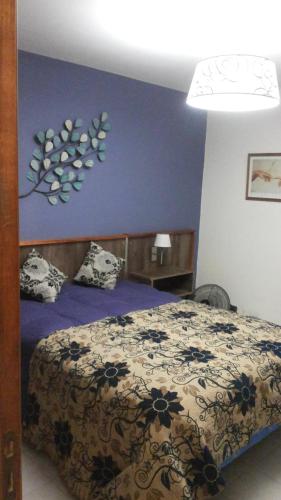 een slaapkamer met een bed met een bloem aan de muur bij Posta Del Cocodrilo in Pinamar