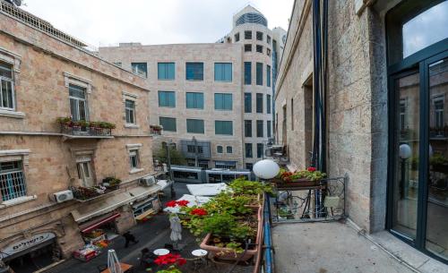 un balcón apartamento con plantas y edificios en el fondo en Kaplan Hotel en Jerusalem