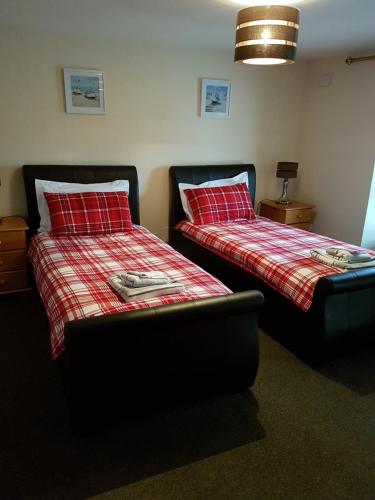 two beds with red pillows in a room at Eilean Donan View in Dornie
