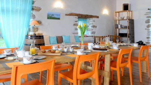 une salle à manger avec une table en bois et des chaises orange dans l'établissement Chambres d'hôtes Idiartekoborda, à Saint-Étienne-de-Baïgorry