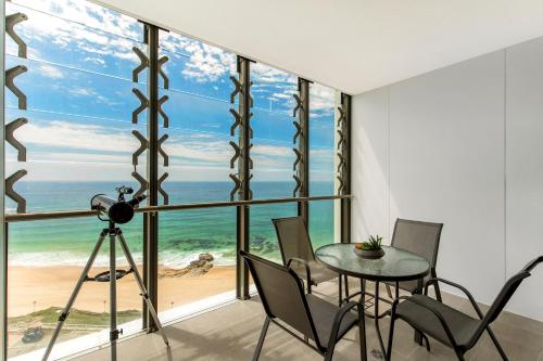 a room with a table and chairs and a view of the ocean at Astra Apartments Newcastle Beach in Newcastle