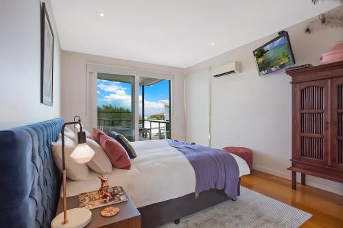 a bedroom with a bed and a couch and a window at 12 Apostles Accommodation Anchors Beach House with sea views in Port Campbell