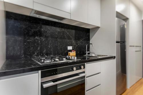 a kitchen with white cabinets and a stove top oven at Astra Apartments Newcastle Beach in Newcastle