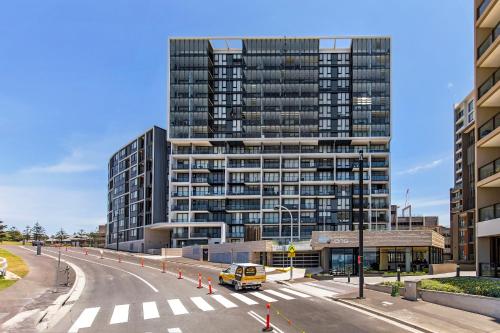 a tall building with a road in front of it at Astra Apartments Newcastle Beach in Newcastle