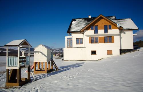 una casa en la nieve con parque infantil en Agroturystyka Słoszówka, en Duszniki-Zdrój