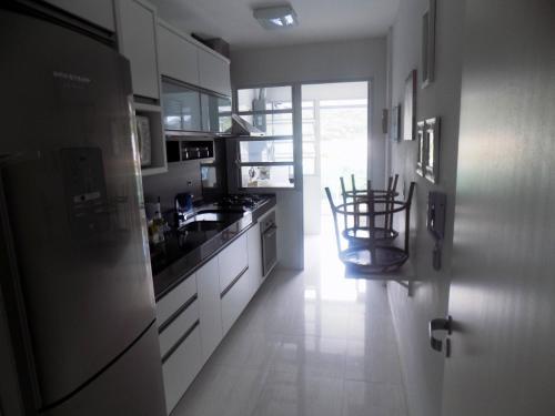 eine Küche mit weißen Schränken und einem Tisch und Stühlen in der Unterkunft Temporada Praia de Palmas SC in Governador Celso Ramos