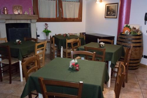 a dining room with green tables and chairs and a fireplace at VillaRosa in Santa Lucia di Piave