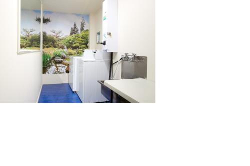 a white kitchen with a sink and a window at Ventura Inn & Suites Hamilton in Hamilton