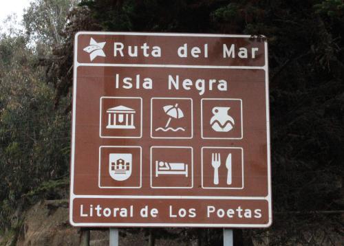 a brown sign with different symbols on a road at Casas Isla Negra in El Quisco