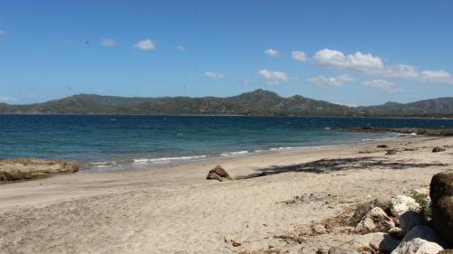 a beach with the ocean and mountains in the background at Flamingo Marina Hotel in Playa Flamingo