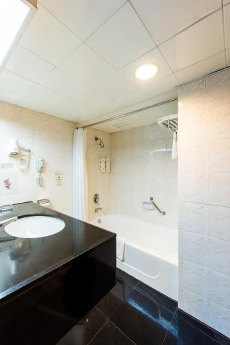 a bathroom with a sink and a bath tub at Inn Hotel Macau in Macau