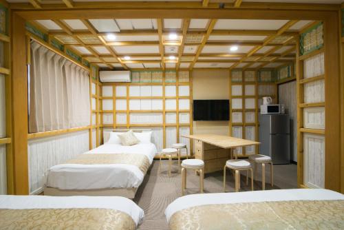 a room with three beds and a table and a desk at ETAVIA Yufuinekimae in Yufuin