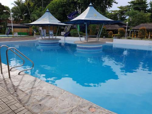 a large swimming pool with blue water and umbrellas at Riverview Resort and Conference Center in Calamba