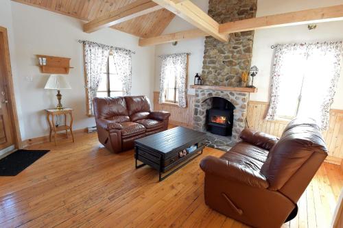 a living room with leather furniture and a fireplace at Le Champ Perché in La Malbaie