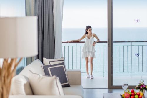 a woman in a white dress standing on a balcony at Cape Sienna Phuket Gourmet Hotel & Villas - SHA Extra Plus in Kamala Beach