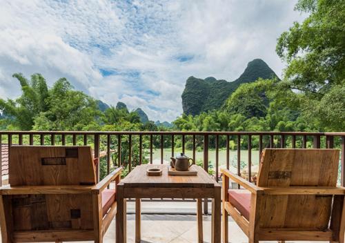two chairs and a table on a balcony with mountains at The Apsara Lodge-Airport or TS Free pick-up over 3 nights in Yangshuo