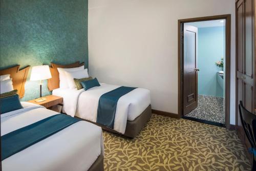 a hotel room with two beds and a bathroom at Mercure Yangon Kaba Aye in Yangon