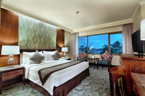 a bedroom with a large bed and a large window at Aston Tropicana Hotel Bandung in Bandung