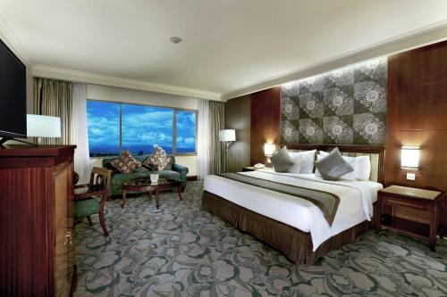 a hotel room with a bed and a large window at Aston Tropicana Hotel Bandung in Bandung