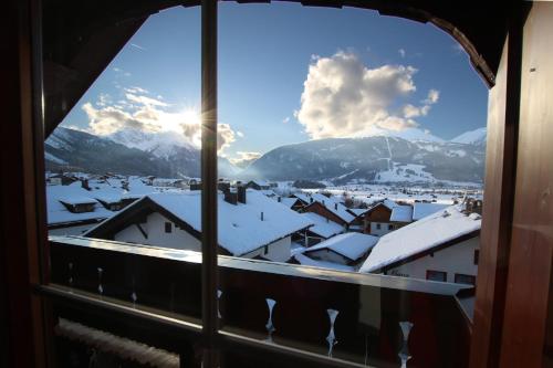a view of a snowy city from a window at Appartementhotel Zugspitzhof in Ehrwald