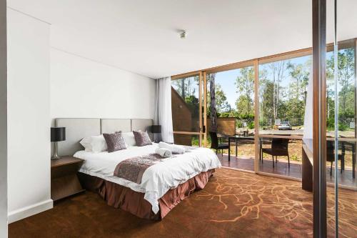 a bedroom with a large bed and a large window at The Kooralbyn Valley in Kooralbyn