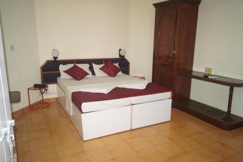 a bedroom with a bed and a wooden cabinet at Hotel Thushara in Kovalam