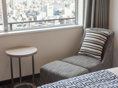 a chair and a stool in a room with a window at Art Hotel Osaka Bay Tower in Osaka