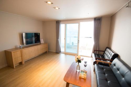 a living room with a couch and a tv at Lium Spa Hostel in Yeosu
