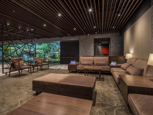 a living room with couches and a table and chairs at Solaria Nishitetsu Hotel Kyoto Premier in Kyoto