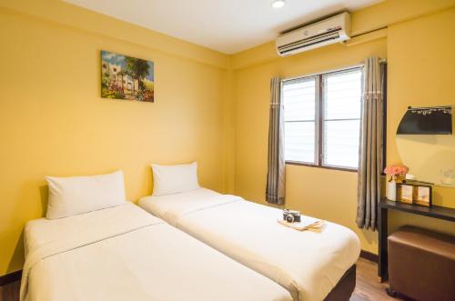 2 łóżka w pokoju z żółtymi ścianami w obiekcie The Corner Ratchada w mieście Bangkok
