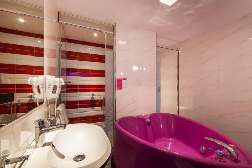 a bathroom with a pink tub and a toilet at 響悅汽車旅館 in Xinwu