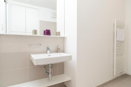 a white bathroom with a sink and a mirror at Luxury Suites Liechtenstein in Vienna