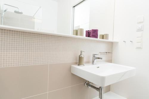 a white bathroom with a sink and a mirror at Luxury Suites Liechtenstein in Vienna
