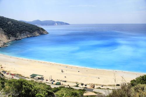 a beach with blue water and people on it at stunning tranquil villa with private pool in Sami