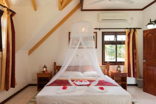 a bedroom with a bed with a mosquito net at Chalets d'Anse Reunion in La Digue