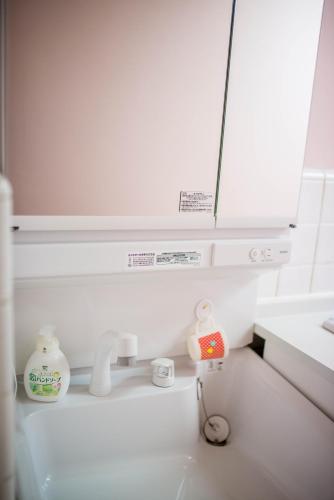 a white kitchen with a sink and a mirror at Kumano House in Kyoto