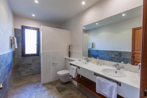 a bathroom with two sinks and a toilet and a mirror at Mansion Ses Oliveres in S'Horta