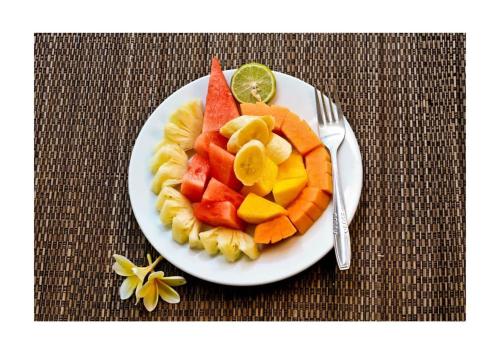 a plate of fruit on a table with a fork at Jagi Villa in Ubud