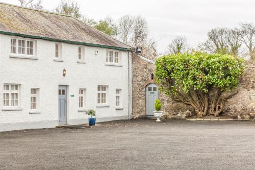 a white house with a tree in front of it at Leixlip Manor Hotel in Leixlip