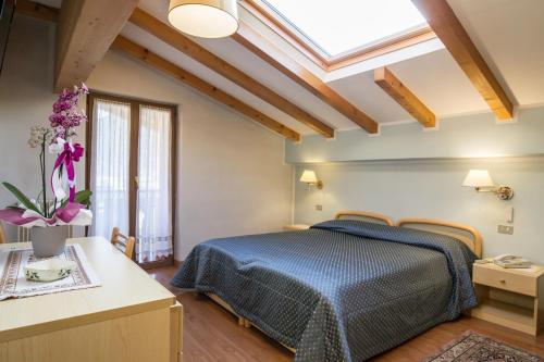 een slaapkamer met een blauw bed en een dakraam bij Hotel Al Prato in Fiera di Primiero