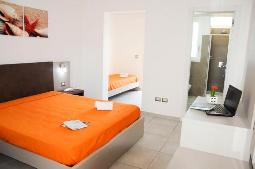 トッレ・ラピッロにあるTorre Lapillo GMA Tourismのベッドルーム1室(オレンジ色のベッド1台、ノートパソコン付きのデスク付)
