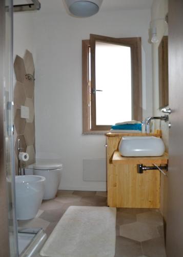 a bathroom with a sink and a toilet and a mirror at Le Perle dell'Isola in Isola Rossa