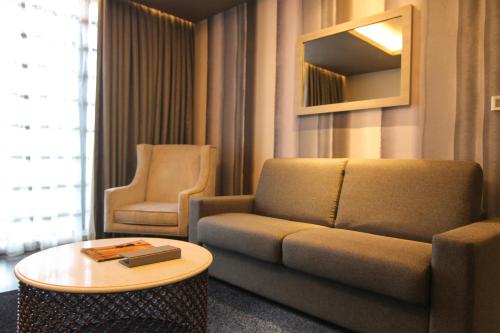a living room with a couch and a table and a chair at bai Hotel Cebu in Cebu City