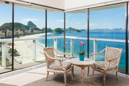 einen Balkon mit einem Tisch und Stühlen sowie Strandblick in der Unterkunft Rio Othon Palace in Rio de Janeiro