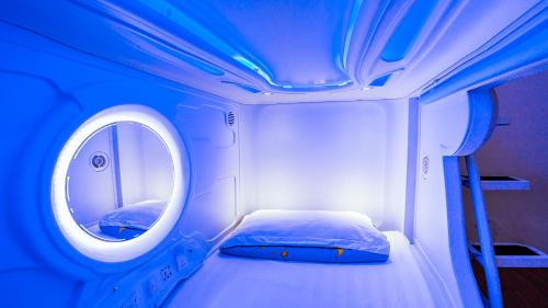 Cette petite chambre comprend un lit et un miroir rond. dans l'établissement Spacepod@com, à Singapour