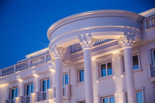 a white building with columns at night at Hotel Villa Pascucci in Durrës