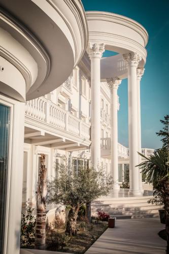 a large white building with columns and trees at Hotel Villa Pascucci in Durrës