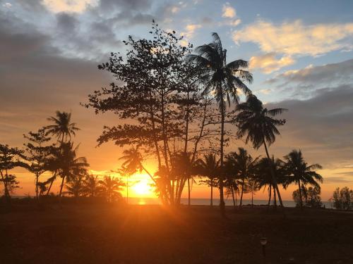 a group of palm trees at sunset on the beach at Sleep Soundly By The Sea in Trat