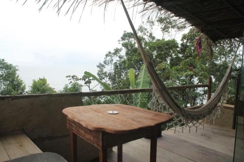 a hammock and a wooden table on a porch at Canto de Paz Trindade Hospedagem in Trindade